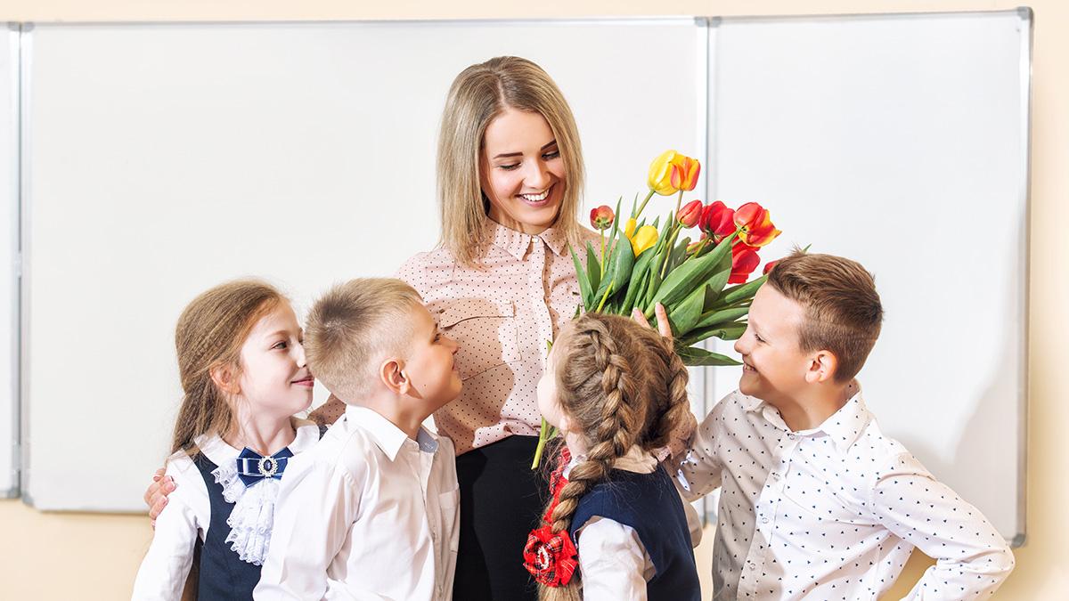 Article Cards Featured Image Beautiful children students together in class at school give flowers to their best woman teacher