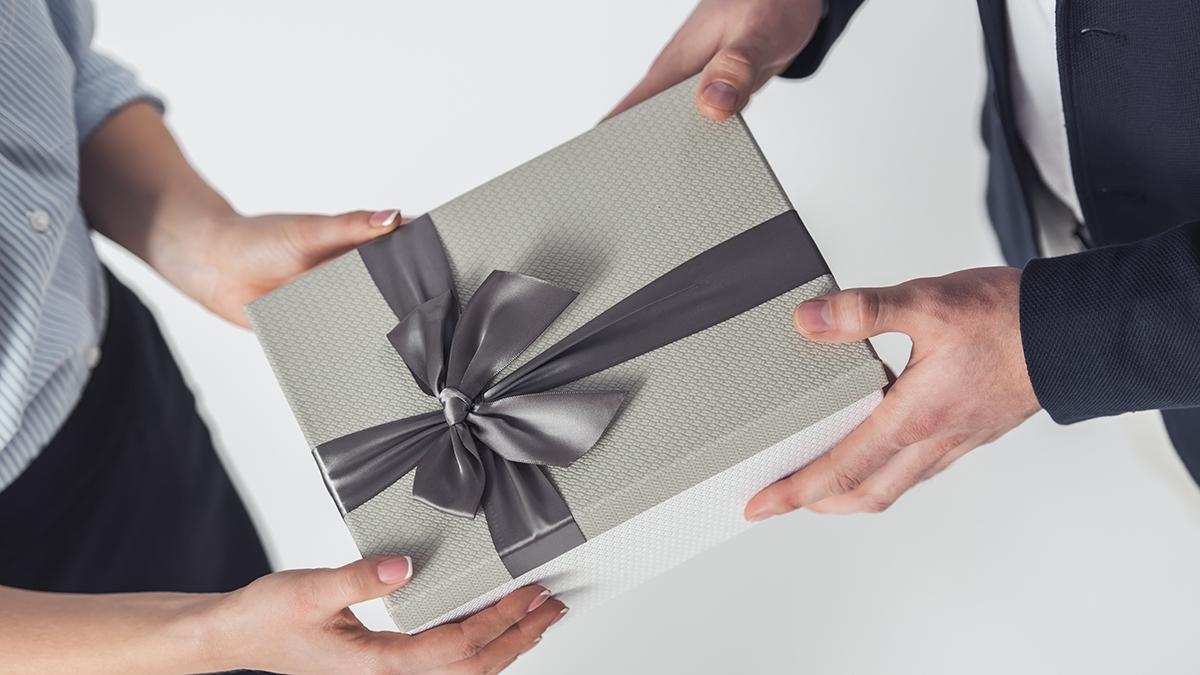 Article Cards Featured Image Cropped image of couple in office clothes holding a gift box, isolated on white