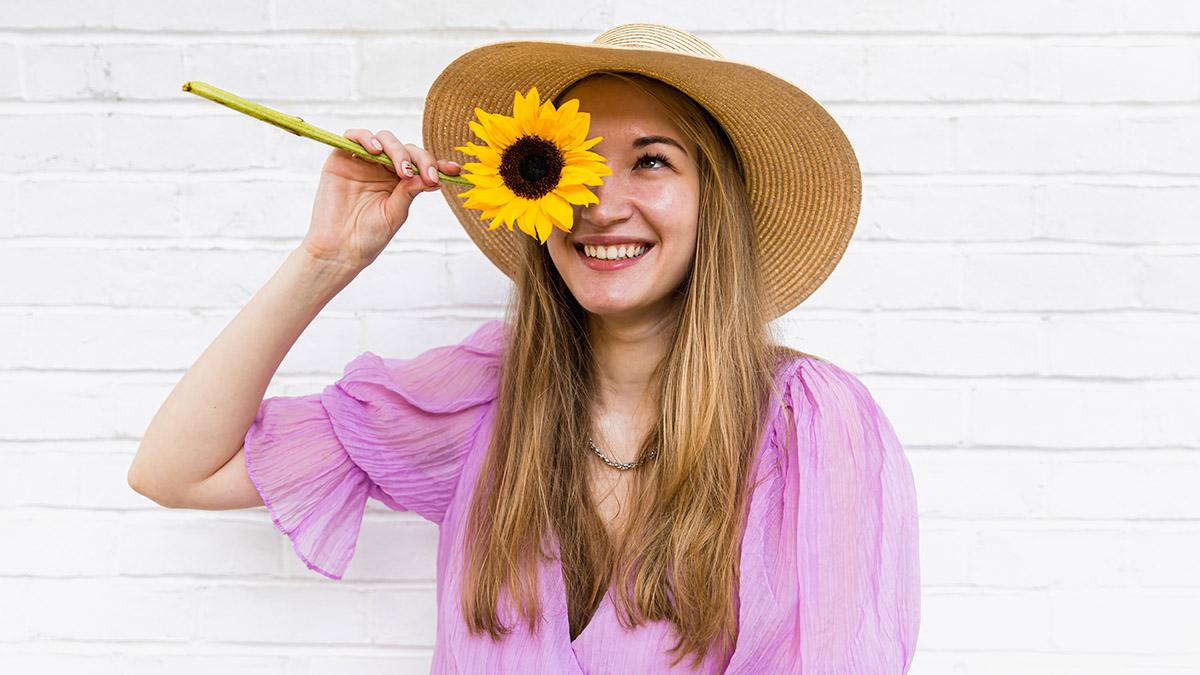 Article Cards Featured Image sunflower symbolism woman holding sunflower in front of face