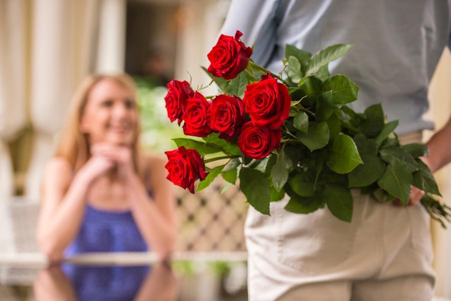 Article Cards Featured Image Young woman looking at man with flower bouquet behind the back.