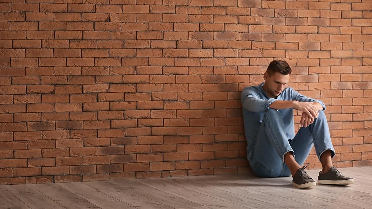 Article Cards Featured Image Depressed young man sitting near brick wall