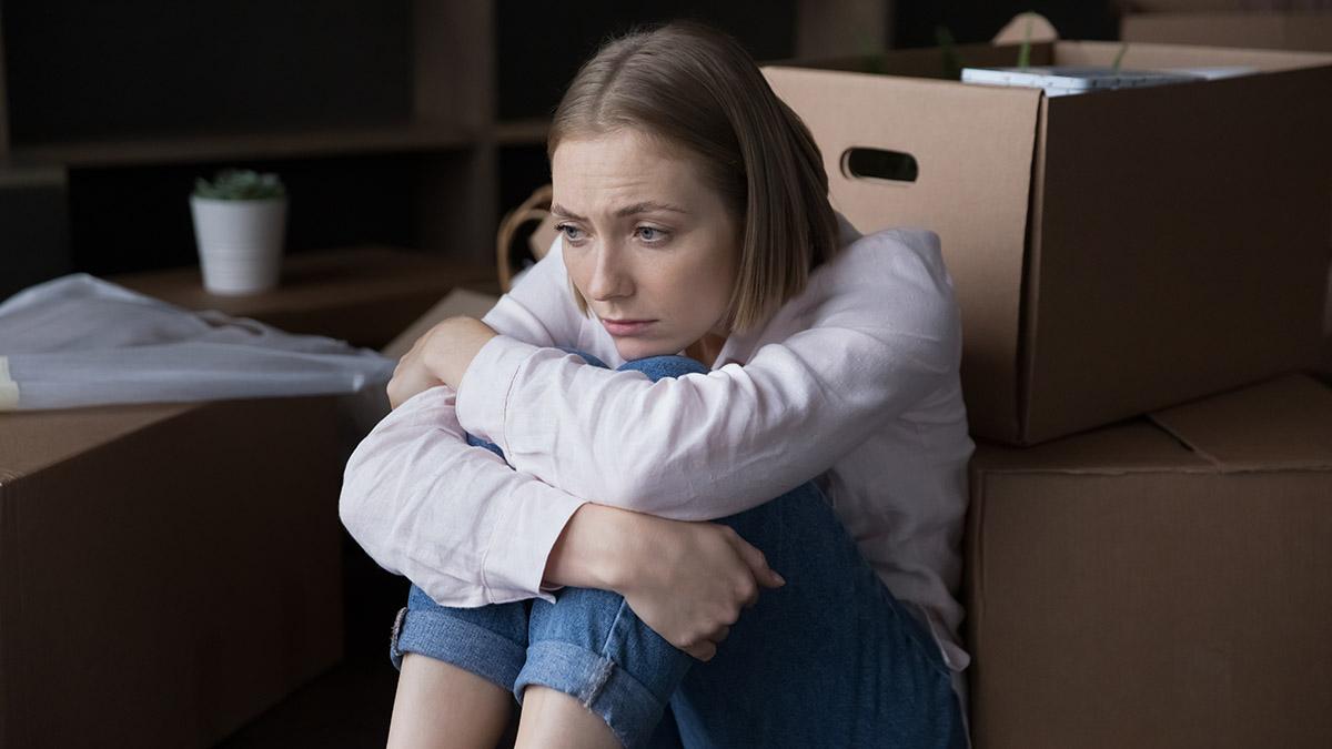 Article Cards Featured Image Sad woman sit near heap of cardboard boxes with belongings