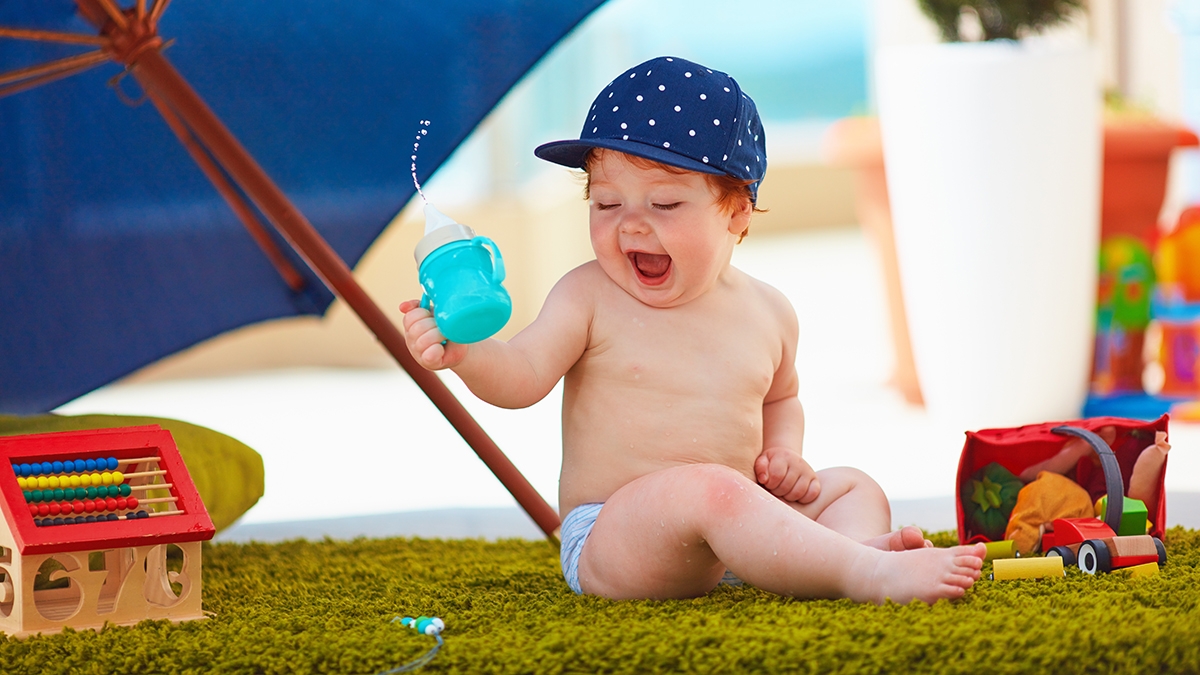 cute infant baby boy having fun outdoors at warm summer day