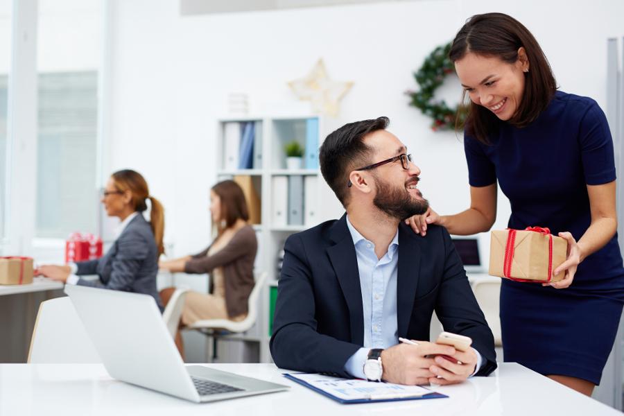 gifts for coworkers with woman giving gift to man in office