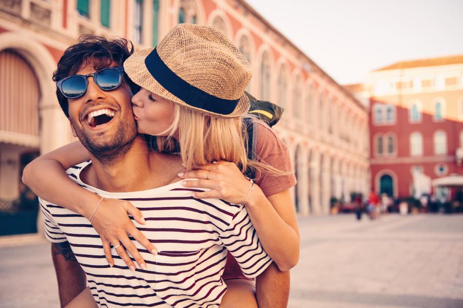 Valentines date ideas with a man giving a piggy back ride to a woman who is kissing his cheek.