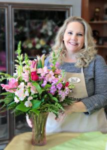 Florist Develyn Reed posing with floral arrangement